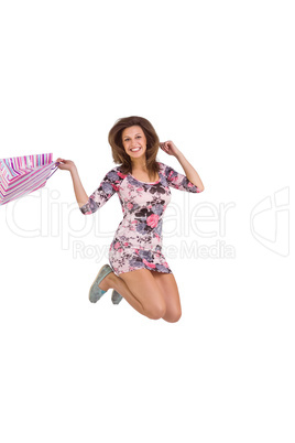 Brunette jumping while holding shopping bags