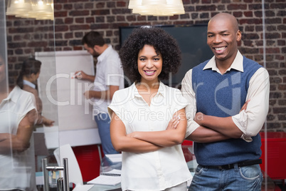 Confident young business people with arms crossed in office