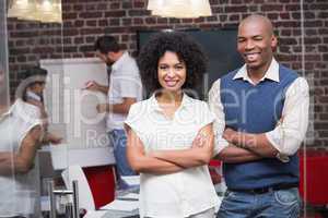 Confident young business people with arms crossed in office