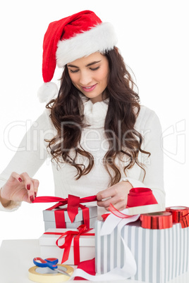 Happy brunette in santa hat packing gifts
