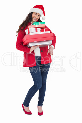 Festive brunette in santa hat and red coat holding pile of gifts