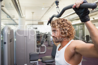 Young man exercising on a lat machine in gym