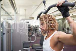 Young man exercising on a lat machine in gym