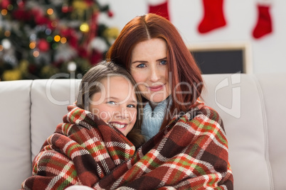 Festive mother and daughter wrapped in blanket