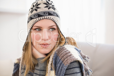 Beautiful blonde in winter hat thinking and looking away