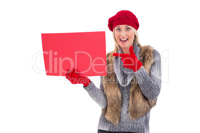 Blonde in winter clothes holding red sign