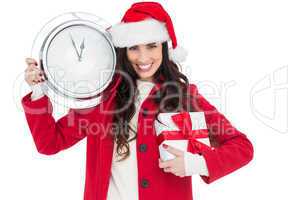 Festive brunette holding a clock and gift