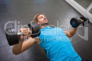 Young man exercising with dumbbells in gym