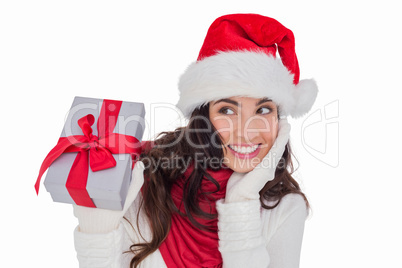 Surprised brunette in santa hat holding gift