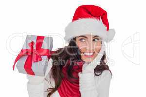 Surprised brunette in santa hat holding gift