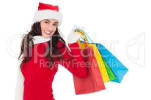 Festive brunette in winter wear holding shopping bags