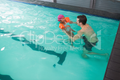 Cute little girl learning to swim with coach