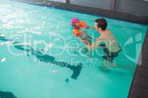 Cute little girl learning to swim with coach