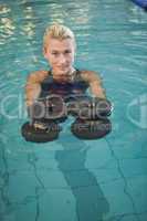 Female swimmer working out with foam dumbbells in swimming pool