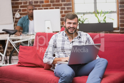 Man using laptop on couch in office