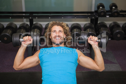 Young man exercising with dumbbells in gym