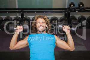 Young man exercising with dumbbells in gym