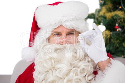 Perplexed santa claus holding his glasses