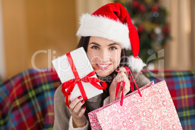 Smiling brunette holding gift and shopping bag  at christmas