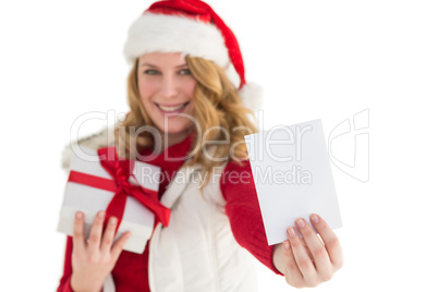 Festive blonde holding christmas gift and showing a card