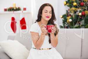 Pretty brunette enjoying a hot drink at christmas