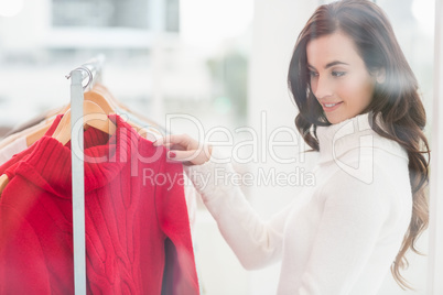 Pretty brunette looking at clothes on rail