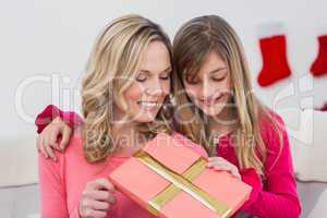 Festive mother and daughter smiling at gift