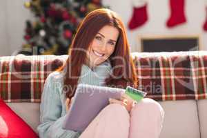 Festive redhead shopping online with tablet