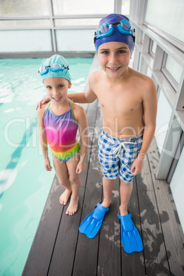 Cute little siblings standing poolside