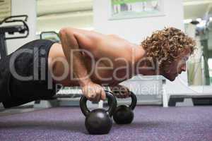 Man doing push ups with kettle bells in gym