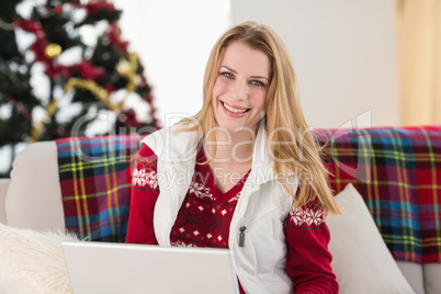Smiling woman sitting on couch using her laptop