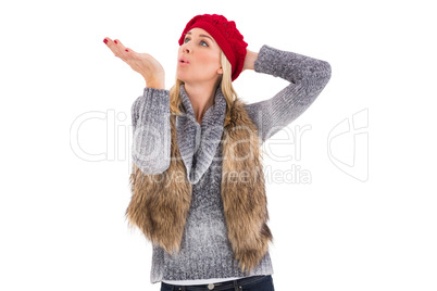 Blonde in winter clothes blowing kiss