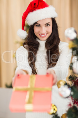 Surprised brunette showing a gift