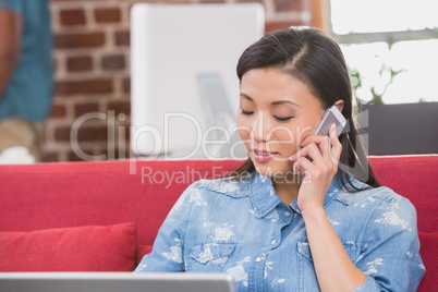 Casual woman using laptop and mobile phone on couch