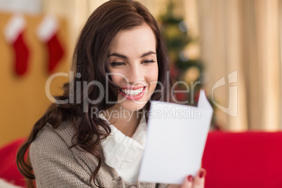 Smiling brunette on the couch reading letter at christmas