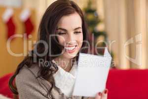 Smiling brunette on the couch reading letter at christmas