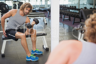Young man exercising with dumbbell in gym