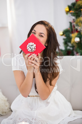 Brunette showing gift on the couch at christmas