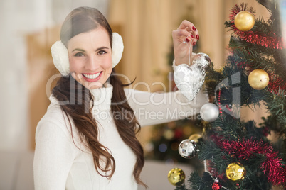 Smiling brunette holding heart near a christmas tree