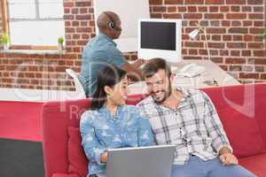 Casual colleagues using laptop on couch