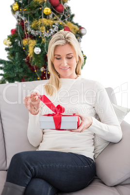 Festive blonde opening christmas gift by the tree