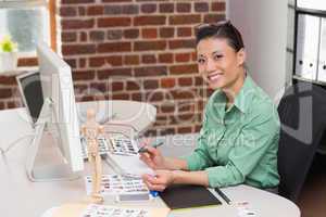 Smiling female photo editor using computer in office