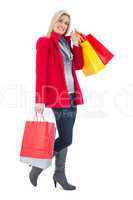 Happy blonde in winter clothes holding shopping bags