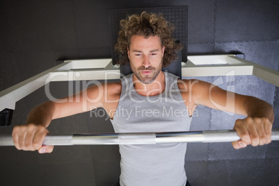 Muscular man lifting barbell in gym