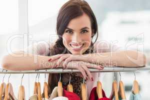 Smiling brunette smiling at camera by clothes rail