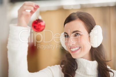 Pretty brunette with ear muffs holding bauble