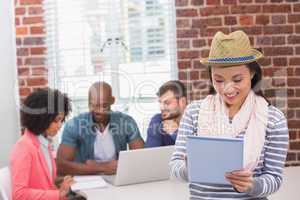 Woman using digital tablet with colleagues behind in office