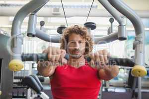 Handsome man working on fitness machine at gym