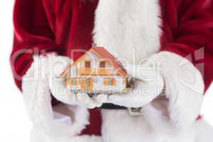 Santa holds a tiny house in his hands