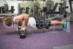 Young man doing push ups with kettle bells in gym